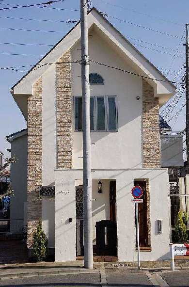 南欧風の煉瓦積み調タイルを隅角部に配し、シンプルな形の家のアクセントに